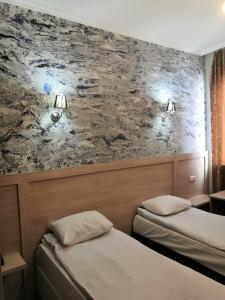 two beds in a hotel room with a wall at Hotel My Rose in Batumi
