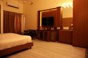 pokój hotelowy z łóżkiem i telewizorem z płaskim ekranem w obiekcie Villa Benares w mieście Waranasi