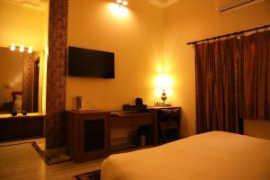 sypialnia z biurkiem i telewizorem na ścianie w obiekcie Villa Benares w mieście Waranasi
