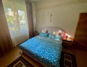 a bedroom with a bed with blue sheets and a window at Grany's Retro Guesthouse near Budapest AirPort in Vecsés