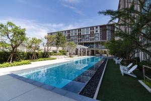 a swimming pool in front of a building at First Choice Suites by the Sea SHA Plus Extra in Hua Hin