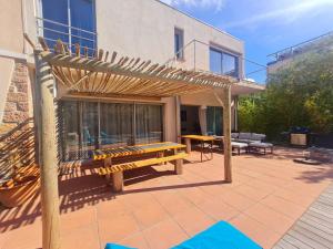 un patio con un banco de madera y una mesa en Coeur de ville maison piscine en Saint-Raphaël