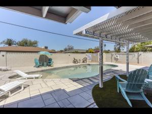 uma piscina com duas cadeiras e um guarda-sol em Scottsdale's Clubhouse Escape em Scottsdale