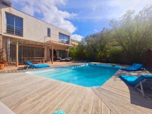 a swimming pool with blue chairs and a house at Coeur de ville maison piscine in Saint-Raphaël