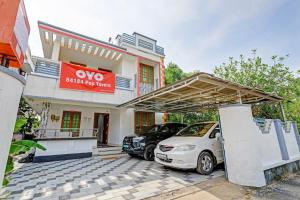 a house with two cars parked in front of it at Capital O 84184 Pop Tavern Kazhakkottam in Vettutura