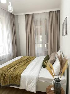 a bedroom with a bed with white sheets and a window at Жк Expo residents in Taldykolʼ
