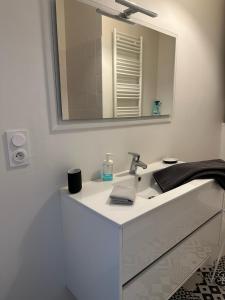 La salle de bains blanche est pourvue d'un lavabo et d'un miroir. dans l'établissement Appartement Design III - Port du Rosmeur - Douarnenez, à Douarnenez