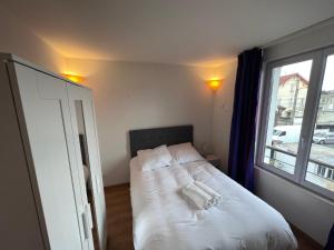 1 dormitorio con 1 cama blanca y ventana en Maison Climatisée 04 chambres Paris Disney CDG, en Gagny