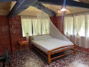 een slaapkamer met een bed in een kamer met ramen bij Borbon's Treehouse By the Sea in Mambajao