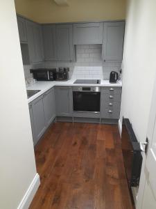 a kitchen with gray cabinets and a wooden floor at Kirkcudbright Holiday Apartments - Apartment E in Kirkcudbright