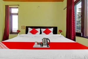 una camera da letto con un letto bianco con cuscini rossi di OYO Hotel Jay Palace a Srinagar