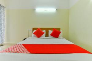 a bedroom with a large bed with red pillows at Hotel Tyche Stays in Trippapur