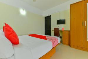 a bedroom with a bed with red pillows and a desk at Hotel Tyche Stays in Trippapur