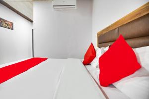 een slaapkamer met rode kussens op een wit bed bij Flagship Hotel Crown in Ludhiana
