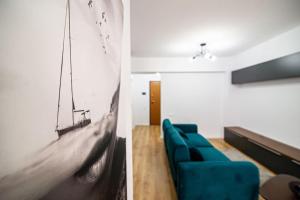 uma sala de estar com um sofá azul e uma fotografia de um barco em City Center Accommodation - 410 em Reşiţa