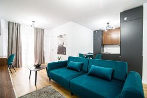 ein Wohnzimmer mit einem blauen Sofa und einer Küche in der Unterkunft City Center Accommodation - 410 in Reşiţa