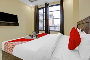 a bedroom with a bed with red pillows and a television at Flagship Hotel Starwood in Jammu