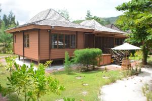 uma pequena casa de madeira com um jardim de relva em Heliconia Grove em Baie Sainte Anne