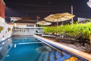 a swimming pool with benches and an umbrella at Sihariddh BnB Villa in Siem Reap