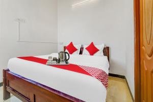 a bedroom with a white bed with red pillows at Flagship Cruze Residency in Coimbatore