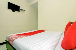 - une chambre avec un lit doté d'oreillers rouges et une télévision dans l'établissement OYO Parimeet Hotel, à Turambhe