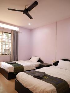 a room with three beds and a ceiling fan at BLANK GUEST HOUSE in Siem Reap