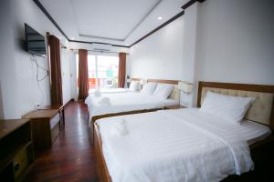 2 camas en una habitación de hotel con TV en Nana Vientiane Hotel en Vientián