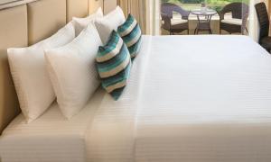 a white bed with pillows on top of it at Sandal Suites by Lemon Tree Hotels in Noida