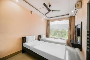 sypialnia z 2 łóżkami i oknem w obiekcie OYO The Orchid w mieście Jamshedpur