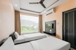 a bedroom with two beds and a tv and a window at Super Hotel O The Orchid in Jamshedpur