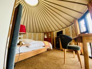a bedroom with a bed and a desk and a chair at APEX Le Yurt Skardu in Skardu