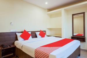 a bedroom with a large bed with red pillows at Hotel O Anu Grand in Visakhapatnam