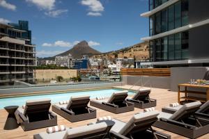 a pool on the roof of a building with lounge chairs at AC Hotel by Marriott Cape Town Waterfront in Cape Town