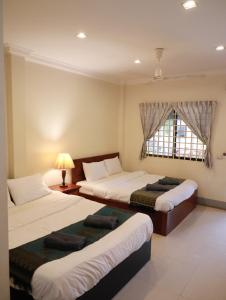 a room with three beds and a window at BLANK GUEST HOUSE in Siem Reap