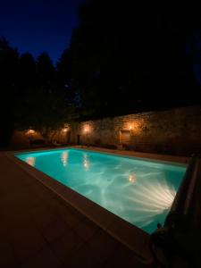 - une piscine avec un mur en pierre la nuit dans l'établissement Domaine de l'Esquibat, à Fumel