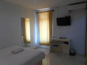 - une chambre avec un lit, un bureau et une télévision dans l'établissement Rumah Syariah Bugenvil, à Bandung