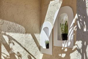 a wall with two arched windows with potted plants at Mila Malia Studios Hotel in Malia