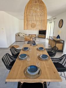 een houten tafel met borden en wijnglazen in de woonkamer bij La Villa Bleue in Saumane-de-Vaucluse