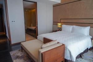 Schlafzimmer mit einem großen weißen Bett mit einem Kopfteil aus Holz in der Unterkunft HUALUXE Hotels & Resorts Nanchang High-Tech Zone, an IHG Hotel in Nanchang
