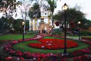 a garden in front of a white house with flowers at Heritage Luxury Suites All Suite Hotel in Lahore