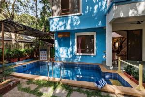 ein blaues Haus mit Pool davor in der Unterkunft SaffronStays Beach Blues, Alibaug in Alibag
