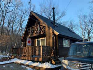 una casa pequeña con porche delantero en la nieve en Log village FIKA / Nasu / Woodstove / Starry sky en Nasu