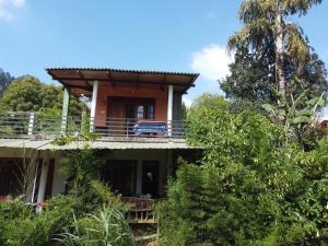 a house with a balcony in the trees at Nature's Glow Home Stay AND RESTAURANT in Ella