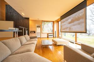 a living room with a couch and a large screen at Lake Toya Villa SUSUKIAN in Sobetsu
