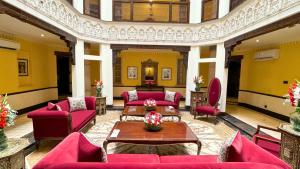 Heritage Luxury Suites All Suite Hotel في لاهور: غرفة معيشة بأثاث احمر وجدران صفراء