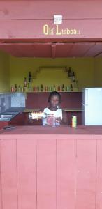 une femme assise à un comptoir rose dans un restaurant dans l'établissement Pousadinha Mar Ave Ilha, à Principe