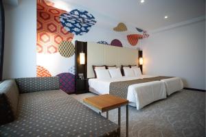 つくば市にあるホテル　ベストランドのベッド2台とソファが備わるホテルルームです。