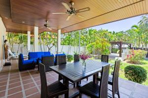 ラワイビーチにある3BR Villa Barnabé with Lush Gardenのダイニングテーブルと椅子、天井ファン付きのパティオ