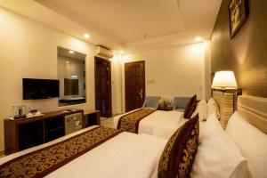 een hotelkamer met 2 bedden en een televisie bij Airport Saigon Hotel - Gần ẩm thực đêm chợ Phạm Văn Hai in Ho Chi Minh-stad