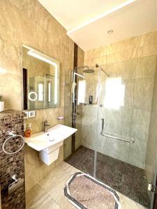 uma casa de banho com um lavatório e um chuveiro com uma porta de vidro em Luxury Sea View 3 Bedrooms, Central AC, WiFi em Rejiche